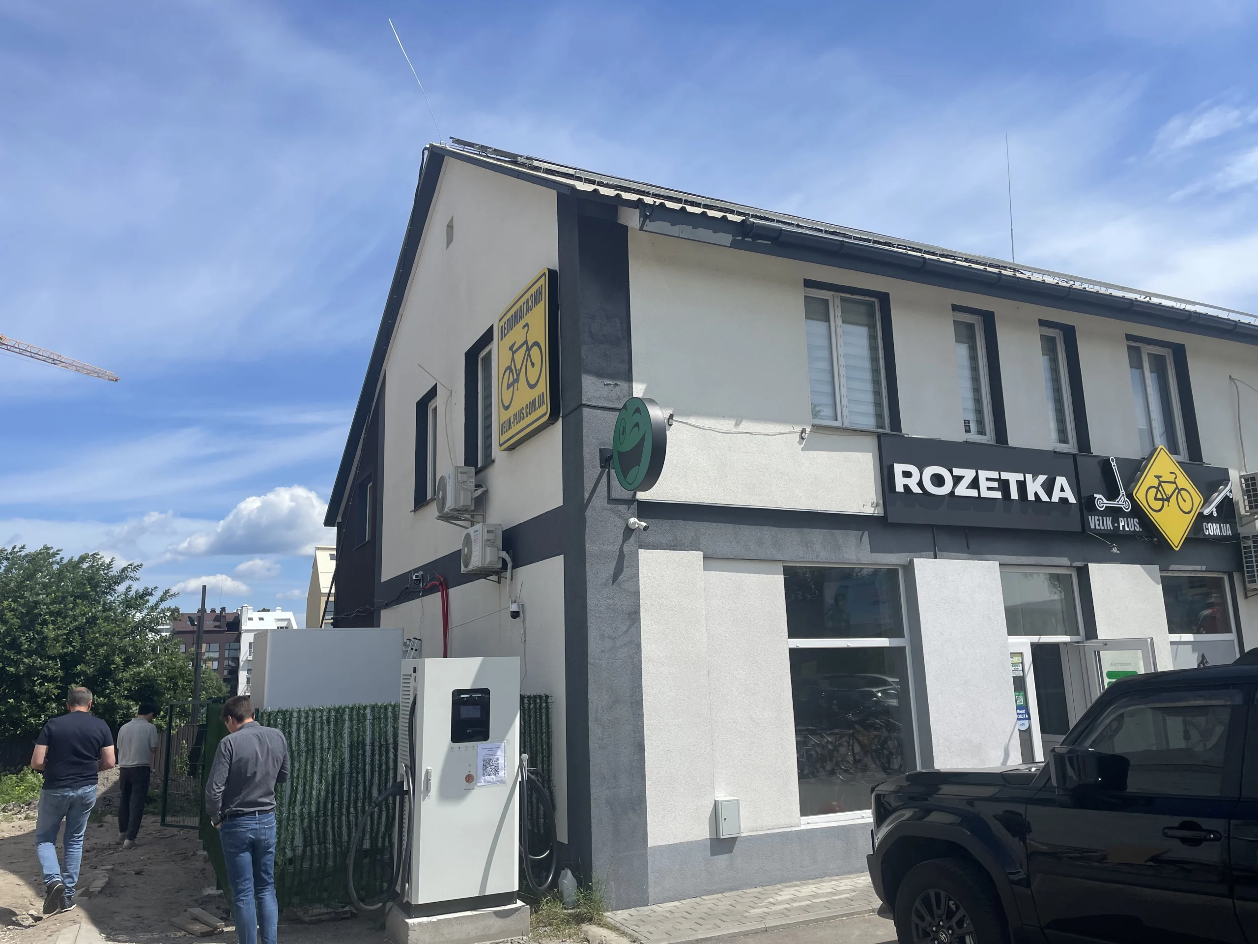EV charging station installation at a Ukraine project site beside a commercial building, showcasing a 100kW/261kWh solar-plus-storage charging setup.