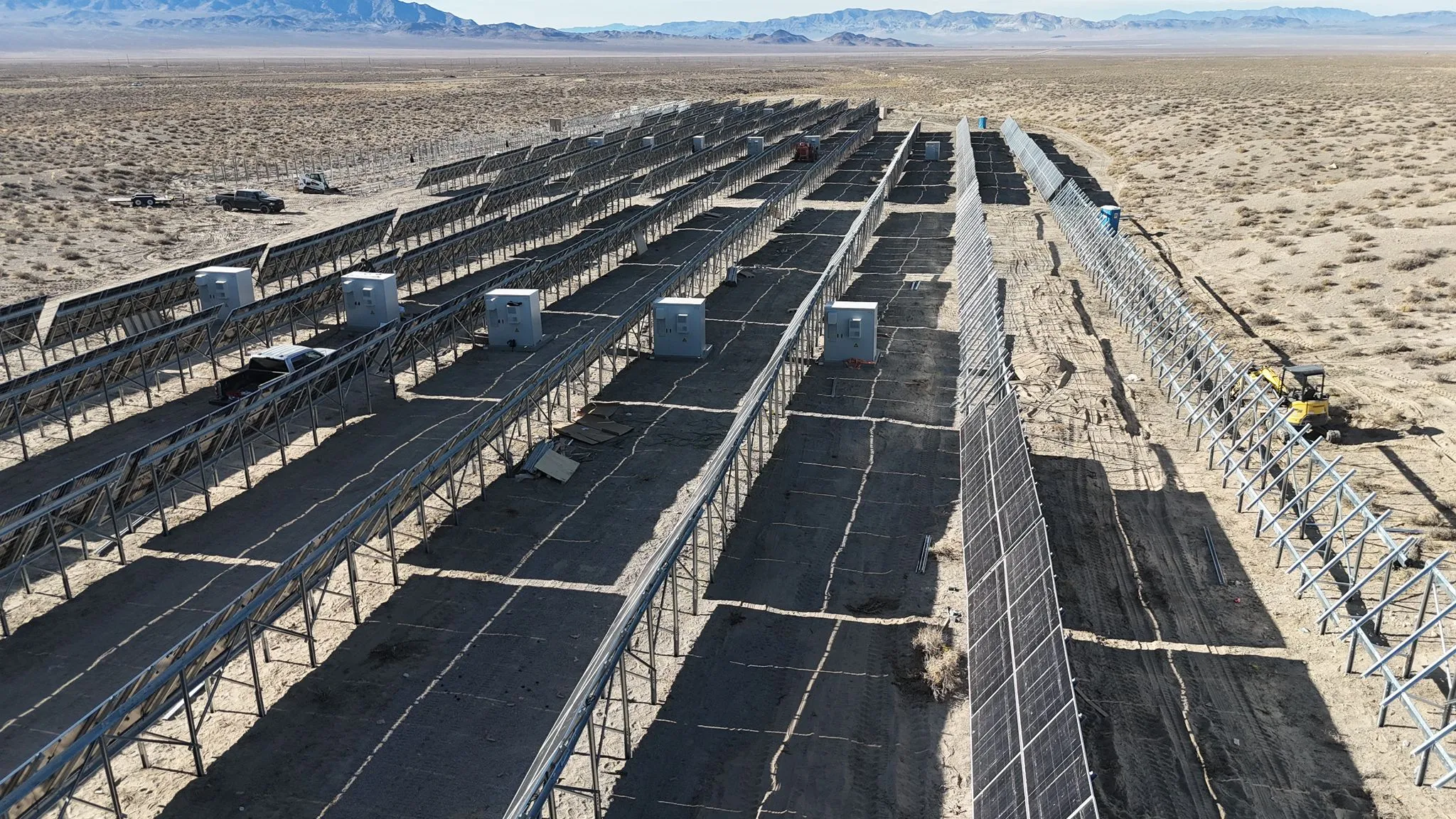 Aerial view of a desert solar site for a 100MWh off-grid data center project, showing long PV rows and equipment enclosures.