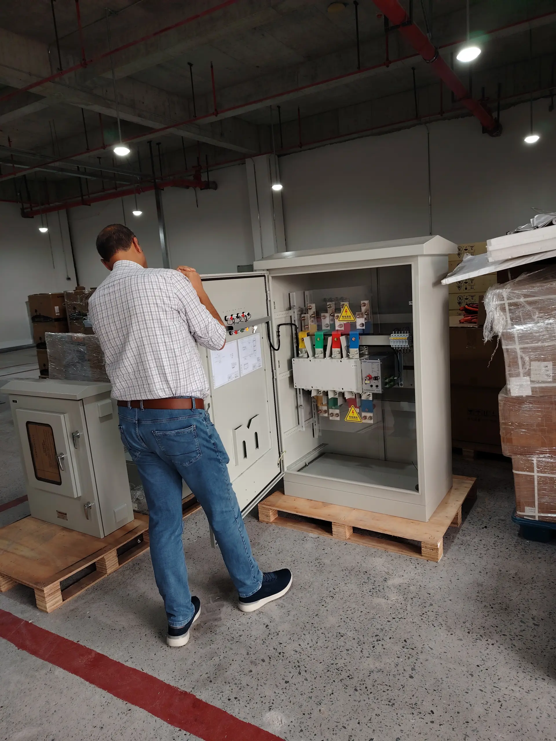 Visitor inspecting the wiring and components inside an open control cabinet during a microgrid equipment demonstration at FFD POWER.