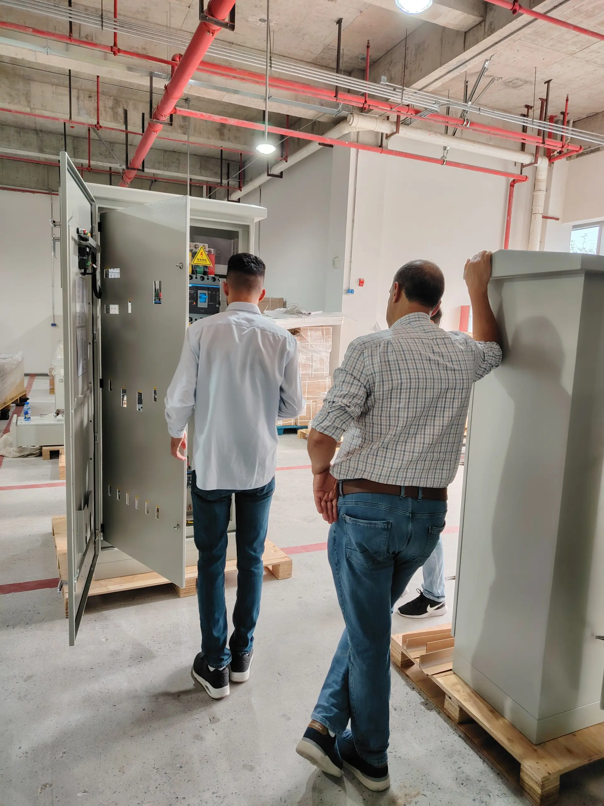 A visitors walking through the facility beside an open electrical cabinet during an FFD POWER microgrid system tour.